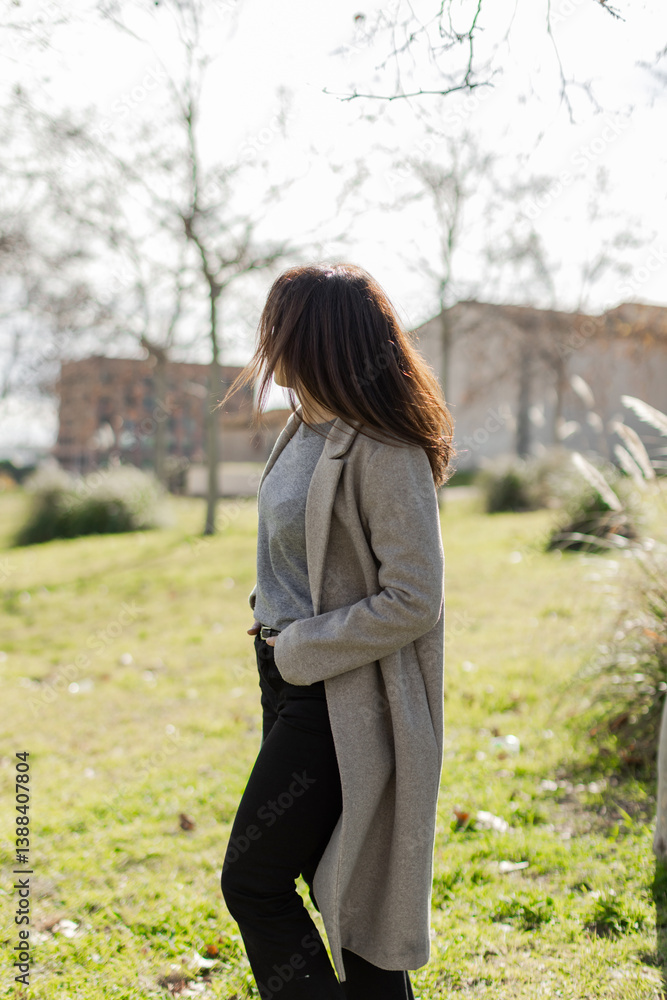 Woman stands outdoors with hands in pockets and hair blowing in the wind. Feels calm, freedom, contemplation. Great for lifestyle, wellness, creativity themes. Vertical, copy-space. Woman stands outdoors with hands in pockets and hair blowing in the wind. Feels calm, freedom, contemplation. Great for lifestyle, wellness, creativity themes. Vertical, copy-space.