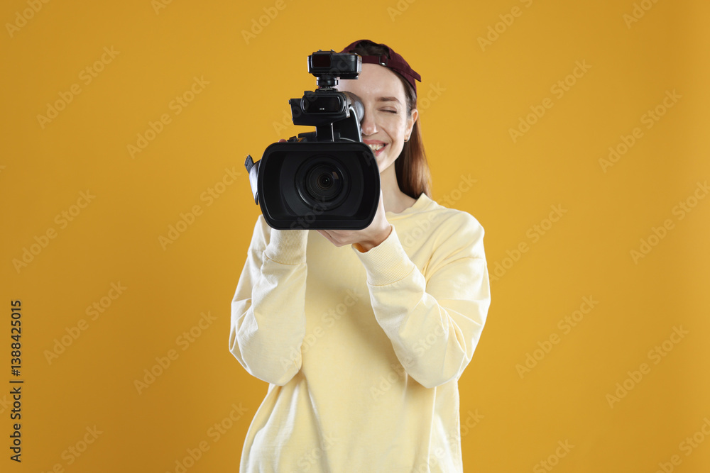 Obraz premium Happy woman with professional video camera on orange background