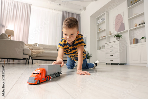 Canvas Print Little boy playing with toy car at home, low angle view