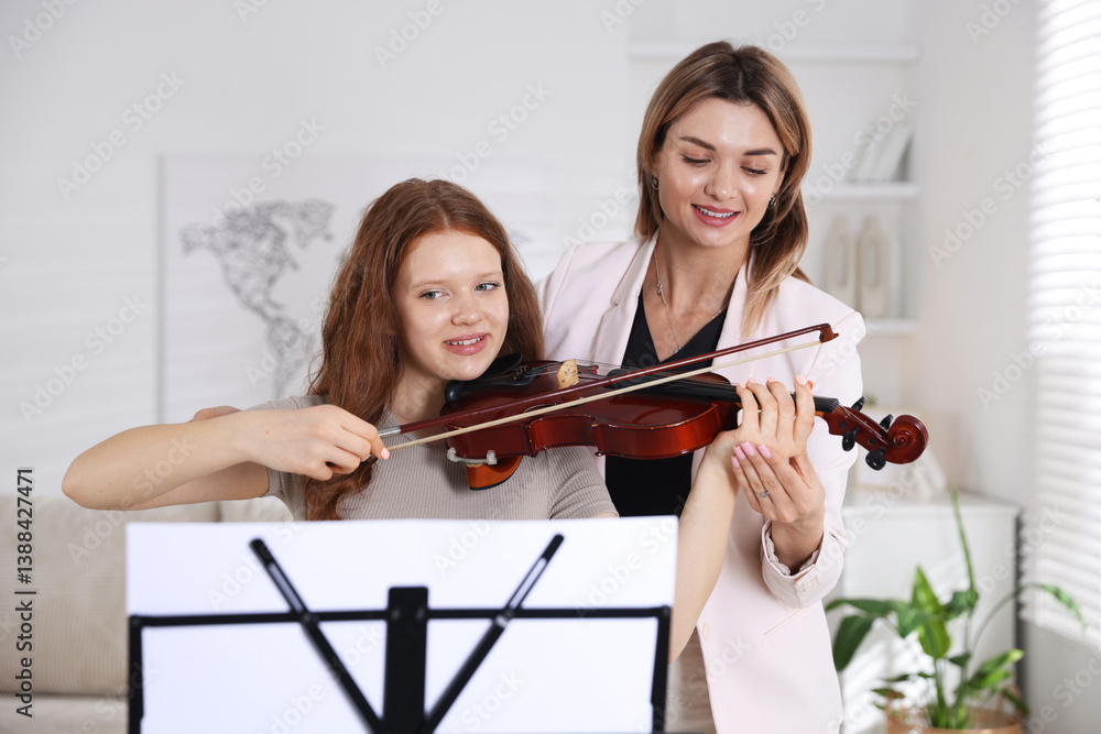 Woman teaching teenage girl to play violin at music lesson