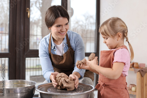 Hobby and craft. Smiling mother with her daughter making pottery indoors