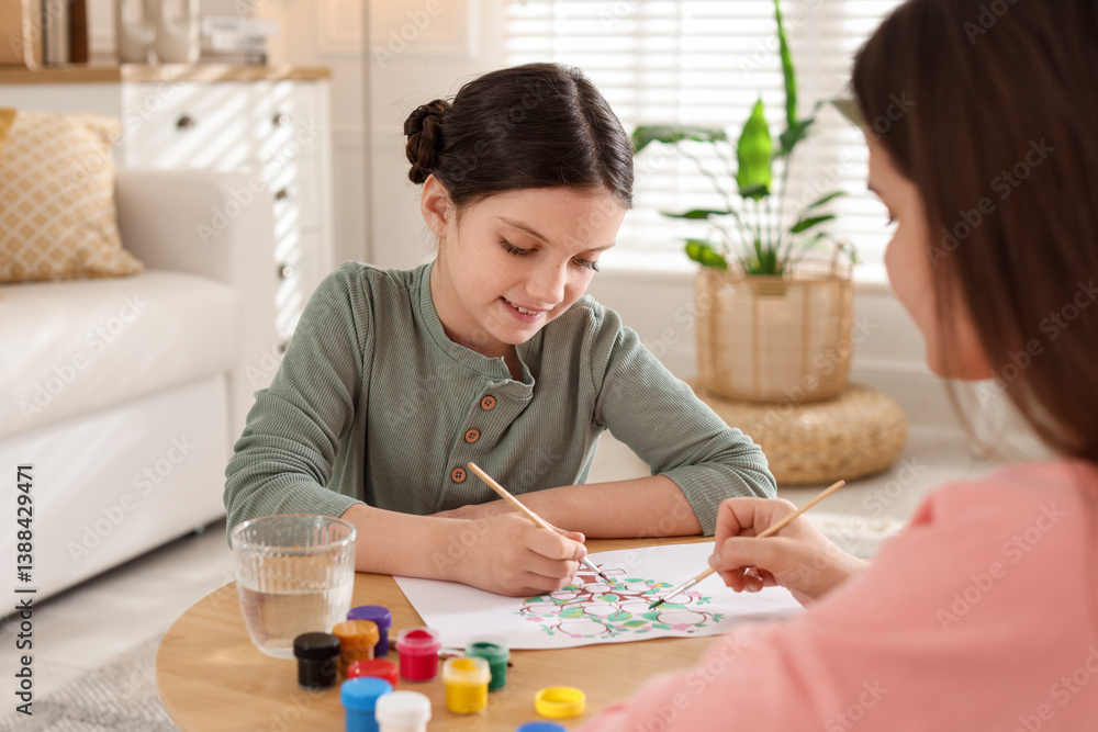 Girl and her mother drawing family tree with paints at wooden table indoors