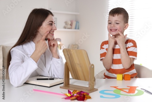 Speech therapist working with little boy indoors