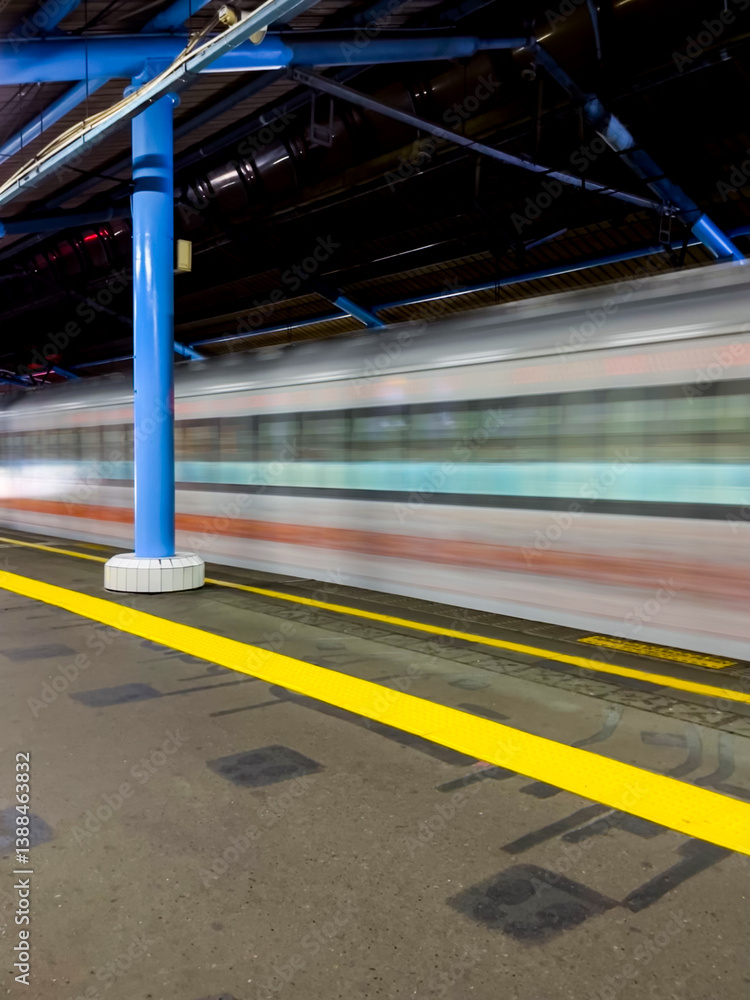 Train platform in Jakarta appears clean and orderly, a passenger train is stopped, yellow safety line clearly visible, bright lights illuminate the area, overall calm and organized atmosphere.