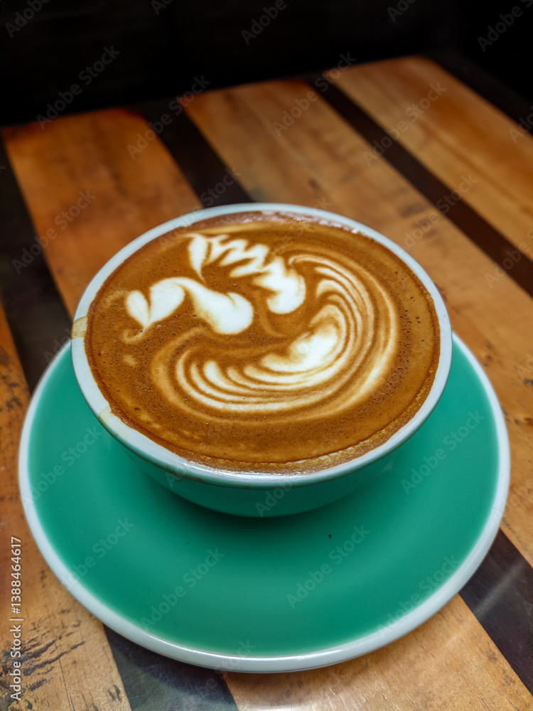 Magic Coffee with two ristretto shots and steamed milk served in a turquoise cup, held over a wooden table with pastries and drinks, capturing a cozy café moment.