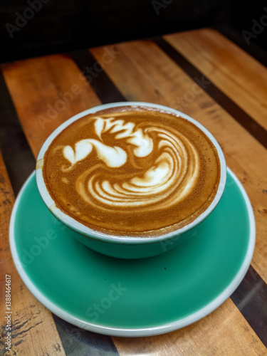 Obraz na płótnie Magic Coffee with two ristretto shots and steamed milk served in a turquoise cup, held over a wooden table with pastries and drinks, capturing a cozy café moment. w salonie