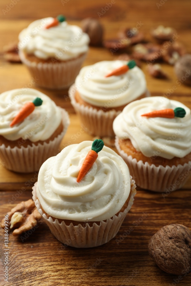 Delicious carrot cupcakes and walnuts on wooden table, closeup Delicious carrot cupcakes and walnuts on wooden table, closeup