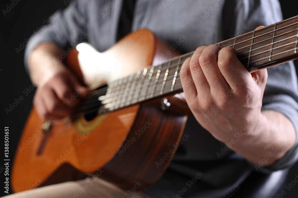 Obraz premium Man playing guitar on black background, focus on hand