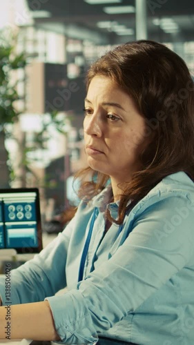 Vertical video Stressed worker in office sighs, burdened by too many documents to review. Tired employee at work feeling overworked while analyzing business performance metrics, camera B
