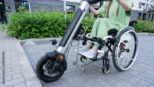 A faceless woman in a wheelchair with an assistive device for manual control. Electric handbike. 