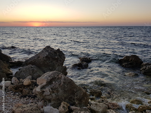 Obraz na płótnie view of the sunset in the sea from a rocky rocky wild beach in summer w salonie