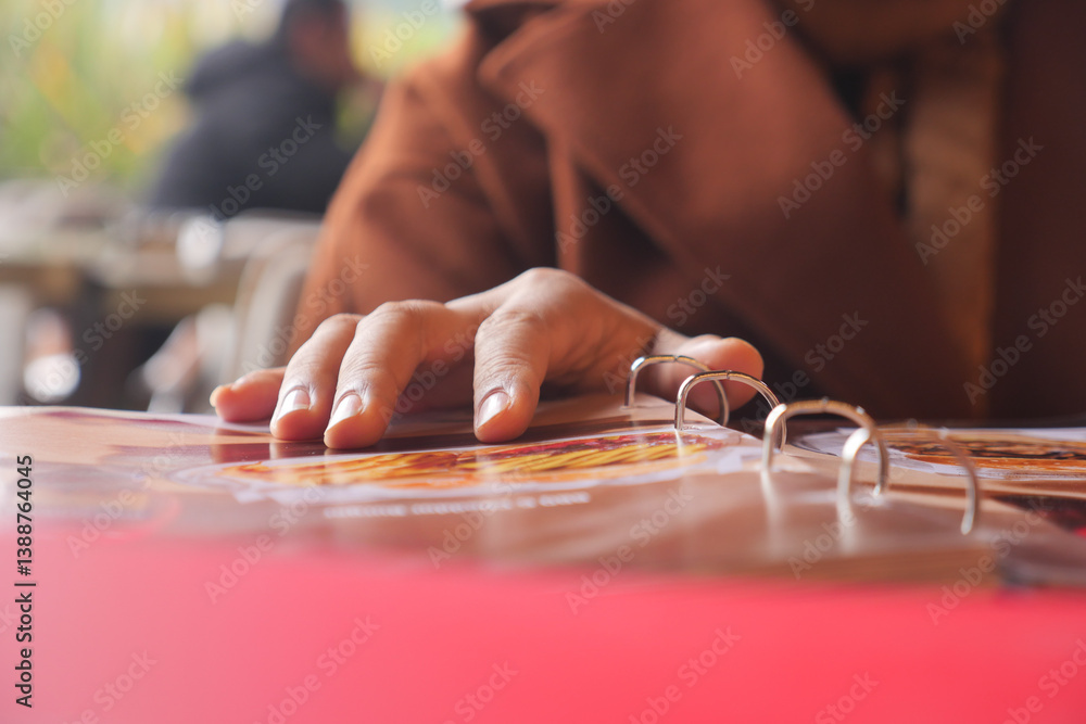 Fototapeta premium Hand reaching for a menu at a cafe on a sunny afternoon