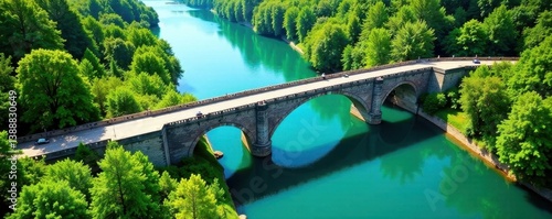 High-angle view of bridge spanning river, lush green banks , sky, water