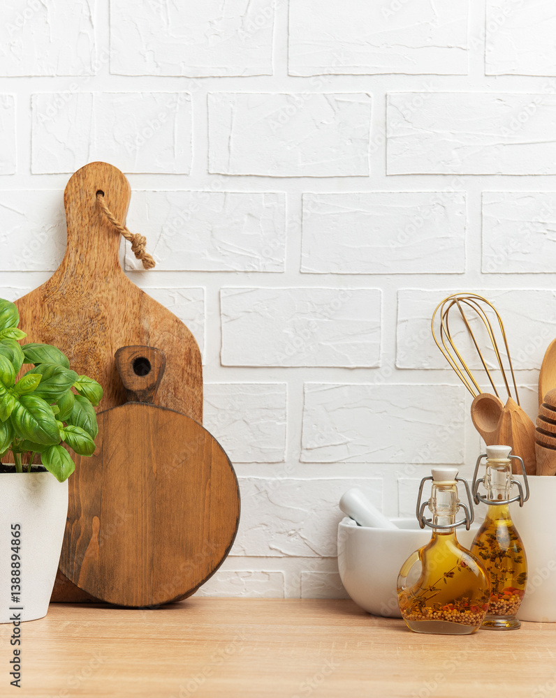 Kitchen utensils, basil plant and spices creating cozy atmosphere on wooden countertop
