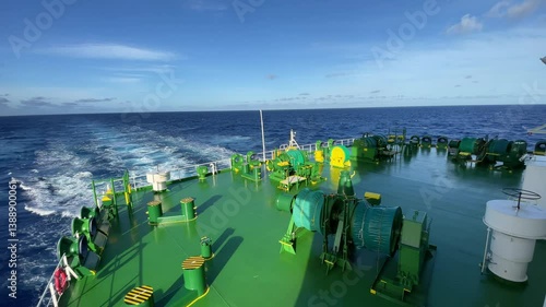 A calm ocean surrounds an LNG ship as the camera captures its vast deck, pipes, and tanks glistening under the sun while it steadily sails through the waves.