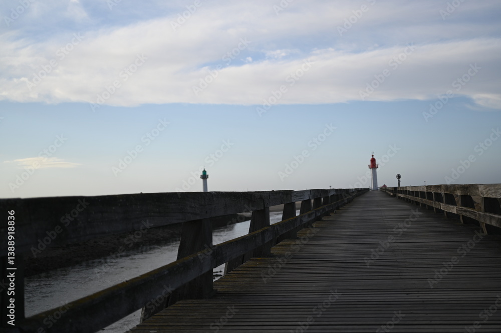 Obraz premium Atlantic Ocean low tide with dark wet shoreline and coastal houses — a calm seaside landscape typical of European Atlantic towns.