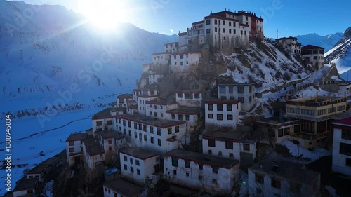 Aerial drone shot capturing the timeless beauty of Key Monastery in the golden hour, as snow blankets the landscape in a serene winter embrace.