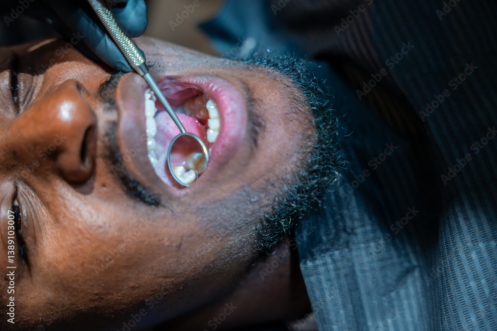 Dentist examining patient's teeth with dental mirror in clinic