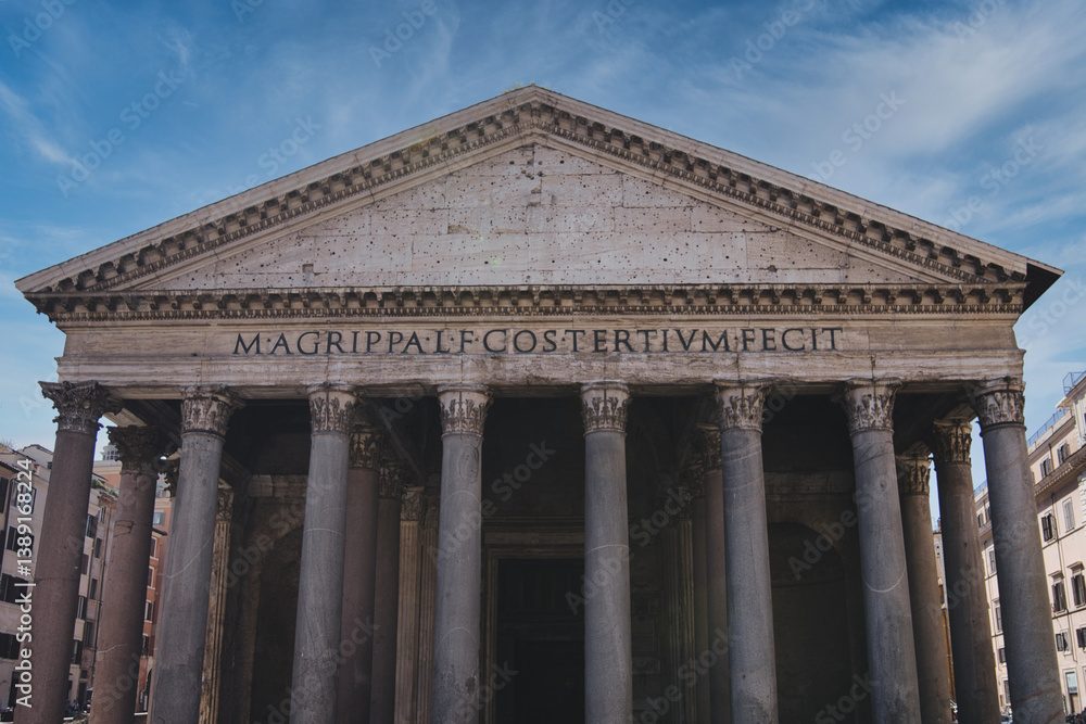 Low angle view of the pantheon's facade in rome, italy, showcasing classical architecture with corinthian columns, a triangular pediment, and the inscription under a vibrant blue sky