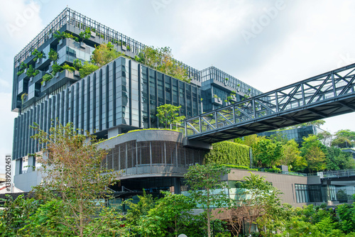 Modern eco-friendly glass office building with vertical garden and skywalk bridge in urban environment in Bangkok city, Thailand. Green architecture and sustainable design for reduce carbon dioxide