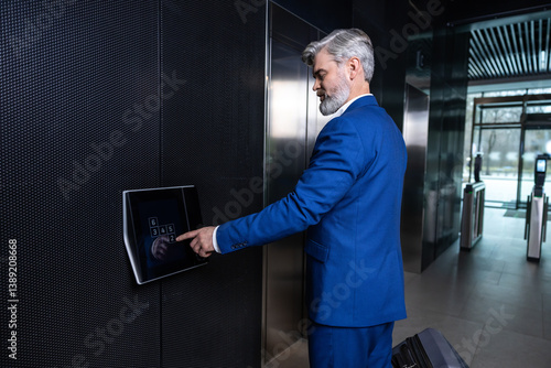 Obraz na plátne Gray-haired elegant businessman pressing the button to call the elevator