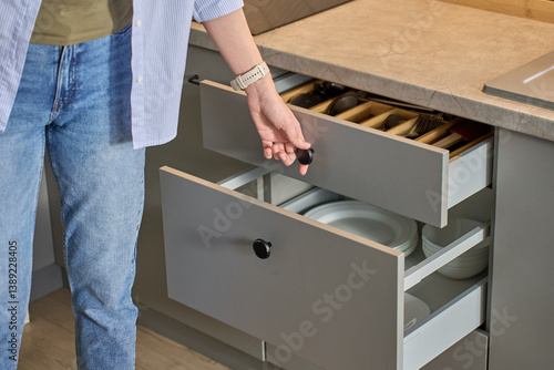 Obraz na płótnie Person opens a kitchen drawer with various utensils in wooden cutlery tray. Woman opening kitchen cabinet. Concept of home organization and functionality interior w salonie