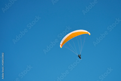 Obraz na płótnie Person is flying on paraglider against blue sky. Paraglide with yellow canopy. Extremal sport w salonie