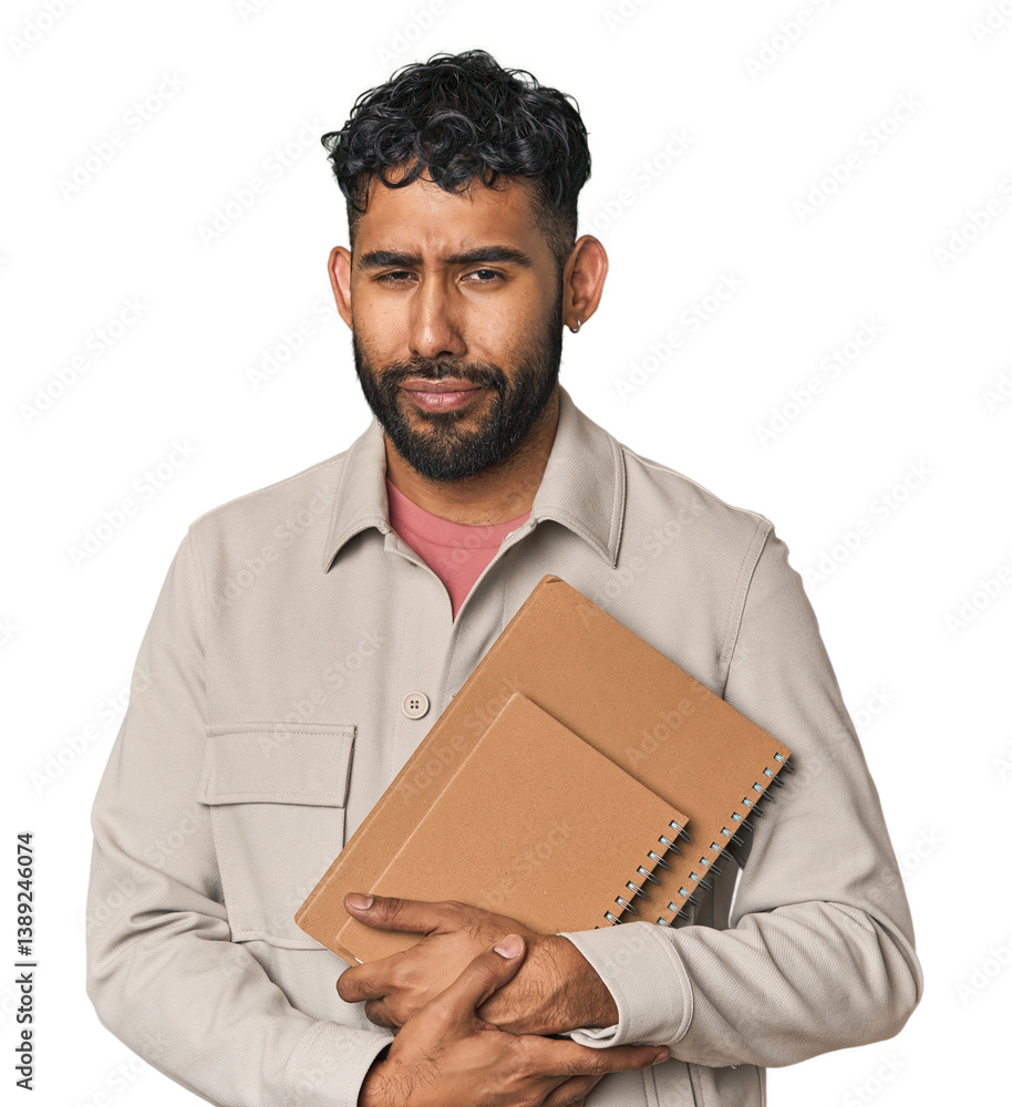 Young Hispanic male student holding notebooks in studio Young Hispanic male student holding notebooks in studio