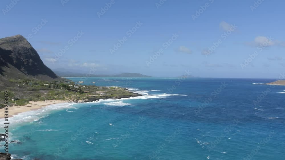Slow pan to the right, showcasing the beach and a mountain with the sky in the background