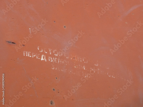 Faded white Cyrillic text on a textured orange surface.