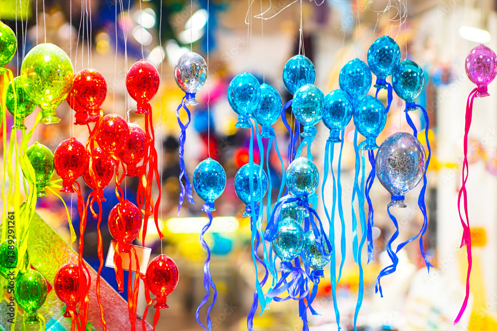 Vibrant glass balloons ornaments in shades of red, blue, and green hang with colorful ribbons, creating a festive display. This lively market scene captures the joy of holiday decorations