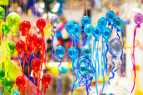 Obraz na płótnie Vibrant glass balloons ornaments in shades of red, blue, and green hang with colorful ribbons, creating a festive display. This lively market scene captures the joy of holiday decorations w salonie