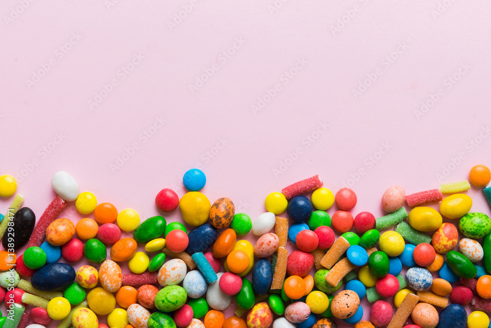 Obraz premium Mixed collection of colorful candy, on colored background. Flat lay, top view. frame of colorful chocolate coated candy