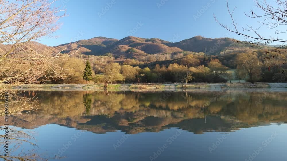 Scenic lake reflecting autumn hills under a clear blue sky, creating a peaceful, mirrored landscape of nature's beauty. Scenic lake reflecting autumn hills under a clear blue sky, creating a peaceful, mirrored landscape of nature's beauty.