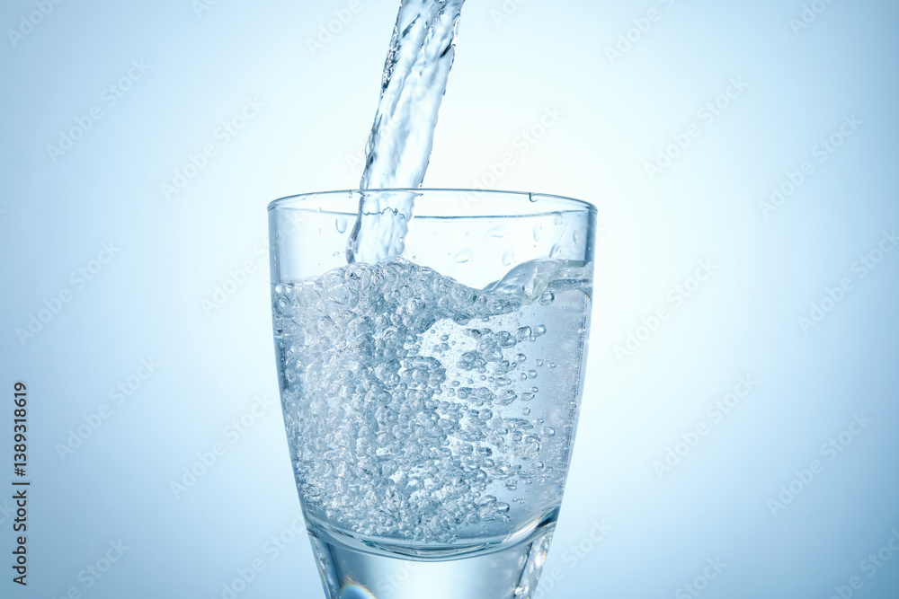 Pouring refreshing soda water into glass on light background, closeup Pouring refreshing soda water into glass on light background, closeup