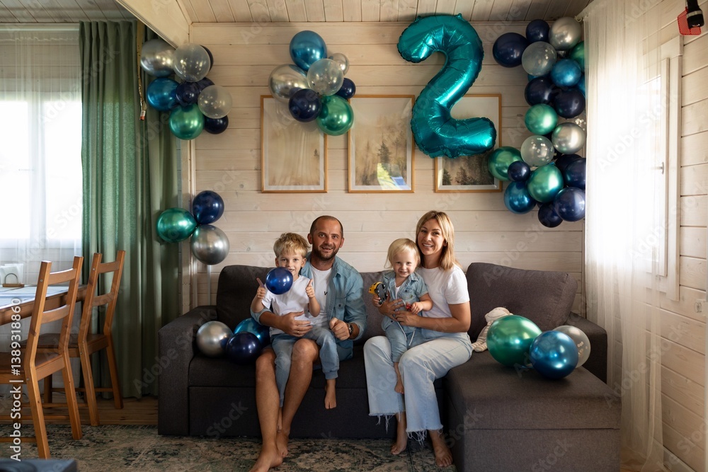 Family celebration featuring two children with balloons in a cozy living room during a joyful birthday party