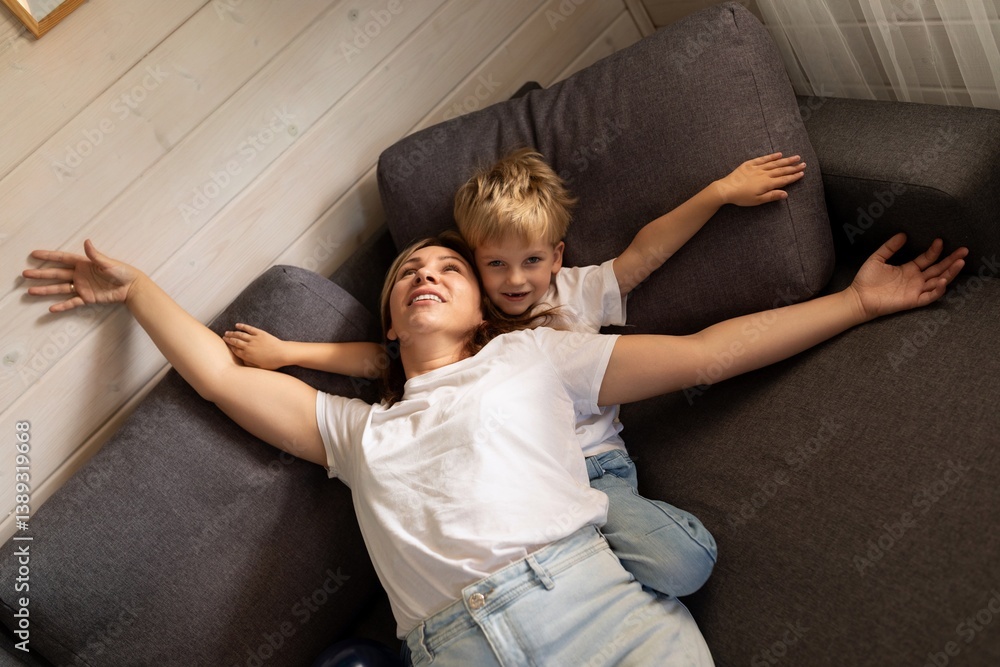 Mother and son enjoying playful afternoon on cozy sofa in living room at home