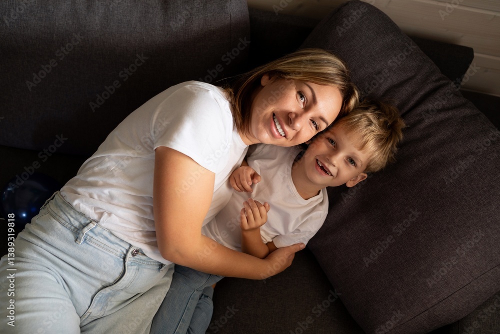 Smiling mother and son share a cozy moment together on the couch in a comfortable living room setting