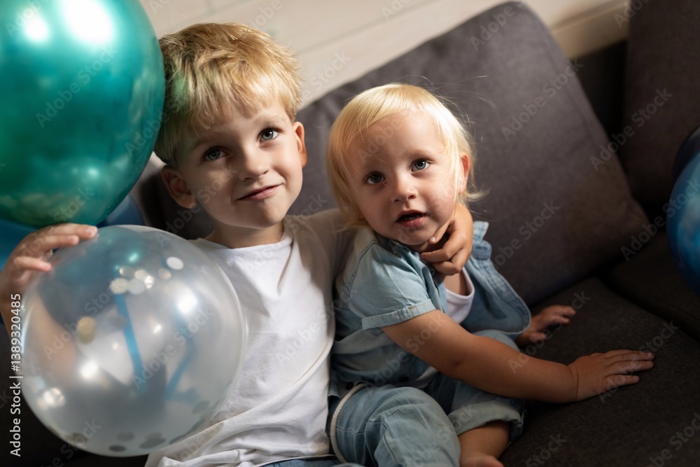 Children celebrating a special occasion with colorful balloons while sitting on a couch at home