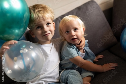 Obraz na płótnie Children celebrating a special occasion with colorful balloons while sitting on a couch at home w salonie