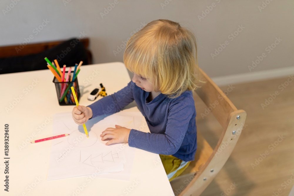 Child engaged in creative drawing activity at a bright indoor workspace during daytime