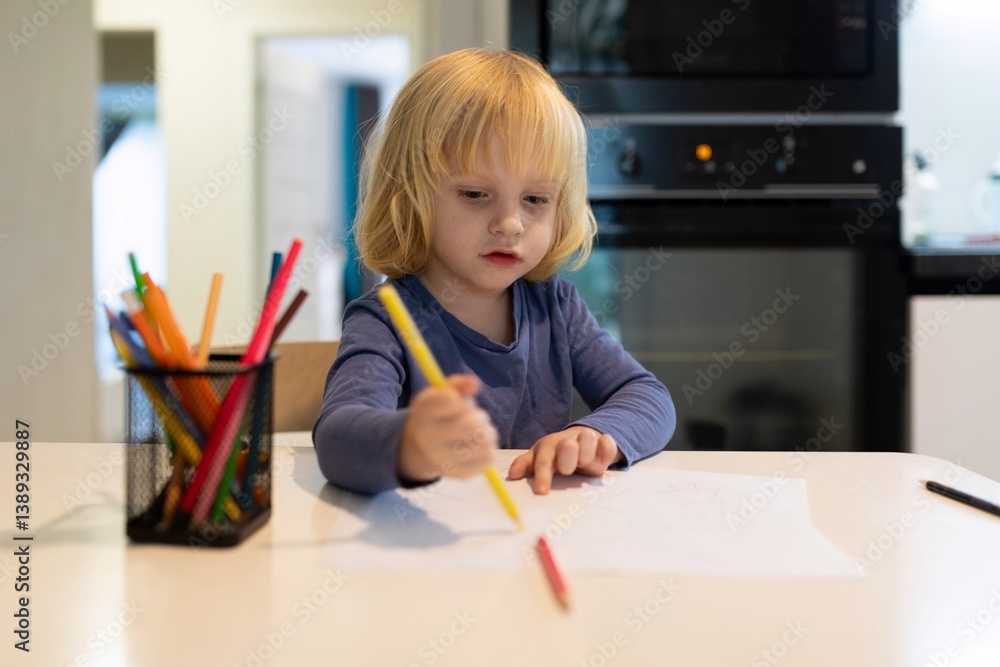 Child engages in creative drawing at kitchen table using colorful markers during daylight hours