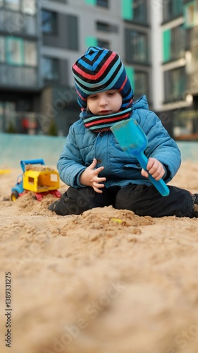 Obraz na płótnie Child playing in sandbox with toys at urban playground during sunny day w salonie