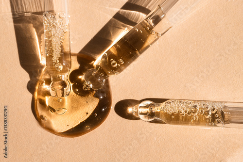 Fotografi Three droppers with essential oil on beige background with sunlight, top view