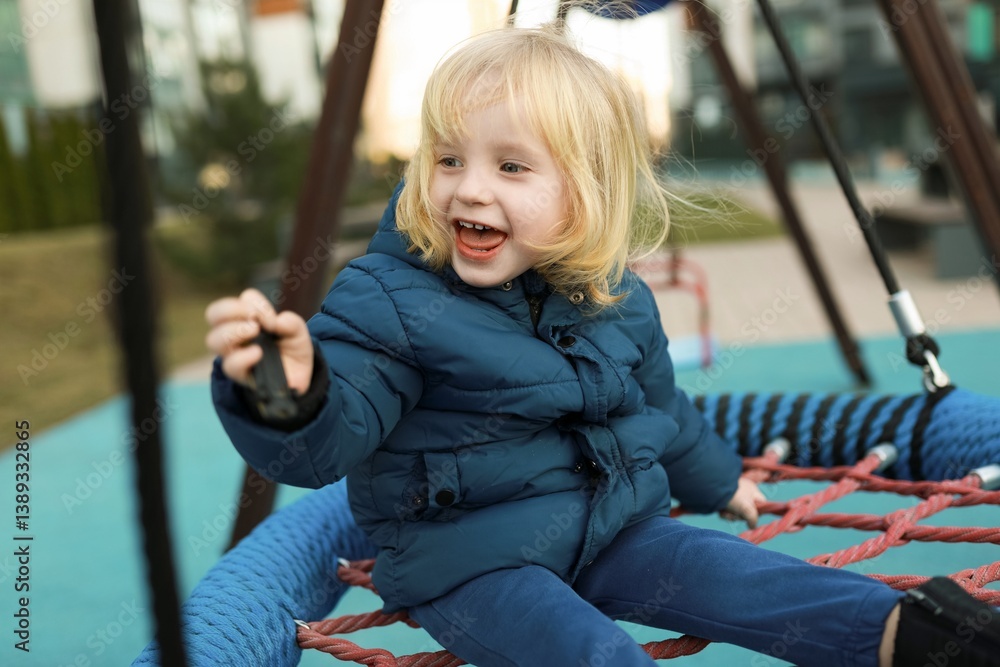 Child joyfully playing on a swing set in a modern playground during a sunny afternoon in a city park