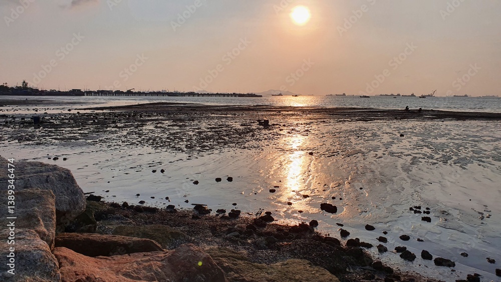 Fototapeta premium Tranquil Sunset Over Calm Ocean with Rocky Shoreline and Reflection on Water Surface
