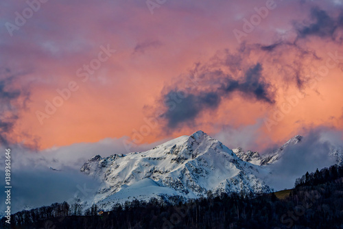 Mountain snowy peak in clouds at dawn. Winter mountain snowy peak in morning sunrise. Snow covered mountain peak