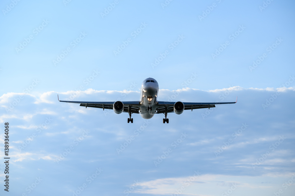 Large passenger jet flying in cloudy blue sky. Unmarked commercial aircraft taking off or landing. Air travel concept, air transport, passenger transportation, turbulence of liner in cloudy weather Large passenger jet flying in cloudy blue sky. Unmarked commercial aircraft taking off or landing. Air travel concept, air transport, passenger transportation, turbulence of liner in cloudy weather