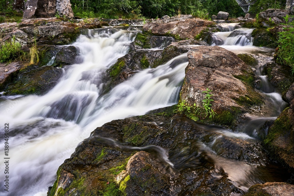 Serene waterfall cascading over rocks surrounded by lush greenery in a forest Serene waterfall cascading over rocks surrounded by lush greenery in a forest