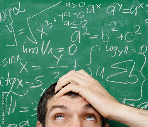 Confused man in front of math formula written on a chalkboard